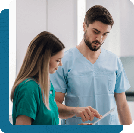 Male and female medical professionals discussing document on clipboard in front of them.