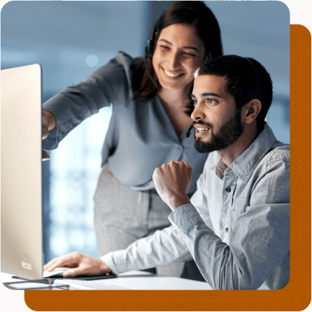 Female and male coworker working together at desk while female points at screen.