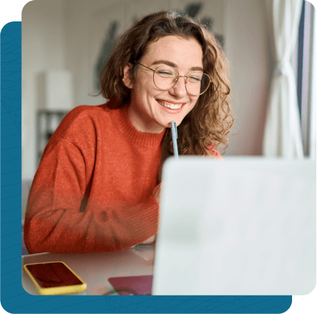 Young woman smiling at computer while sitting at desk.