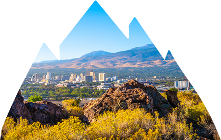 View of city of Nevada from valley with large buildings and mountains in the distance.