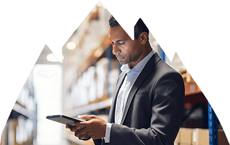 Male businessman in suit standing in factory using his tablet.