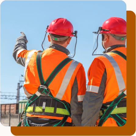 Two utility workers with backs turned to camera talking and pointing into distance.