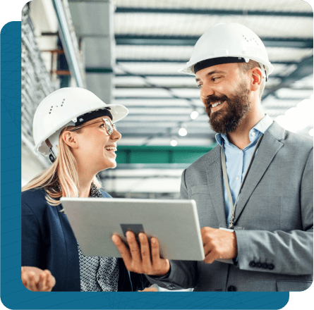 Male and female factory workers smiling at one another and talking.