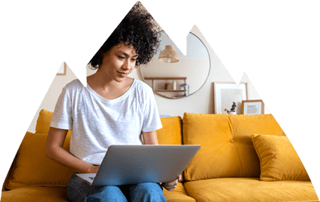 Woman working on laptop while sitting on couch in living room.