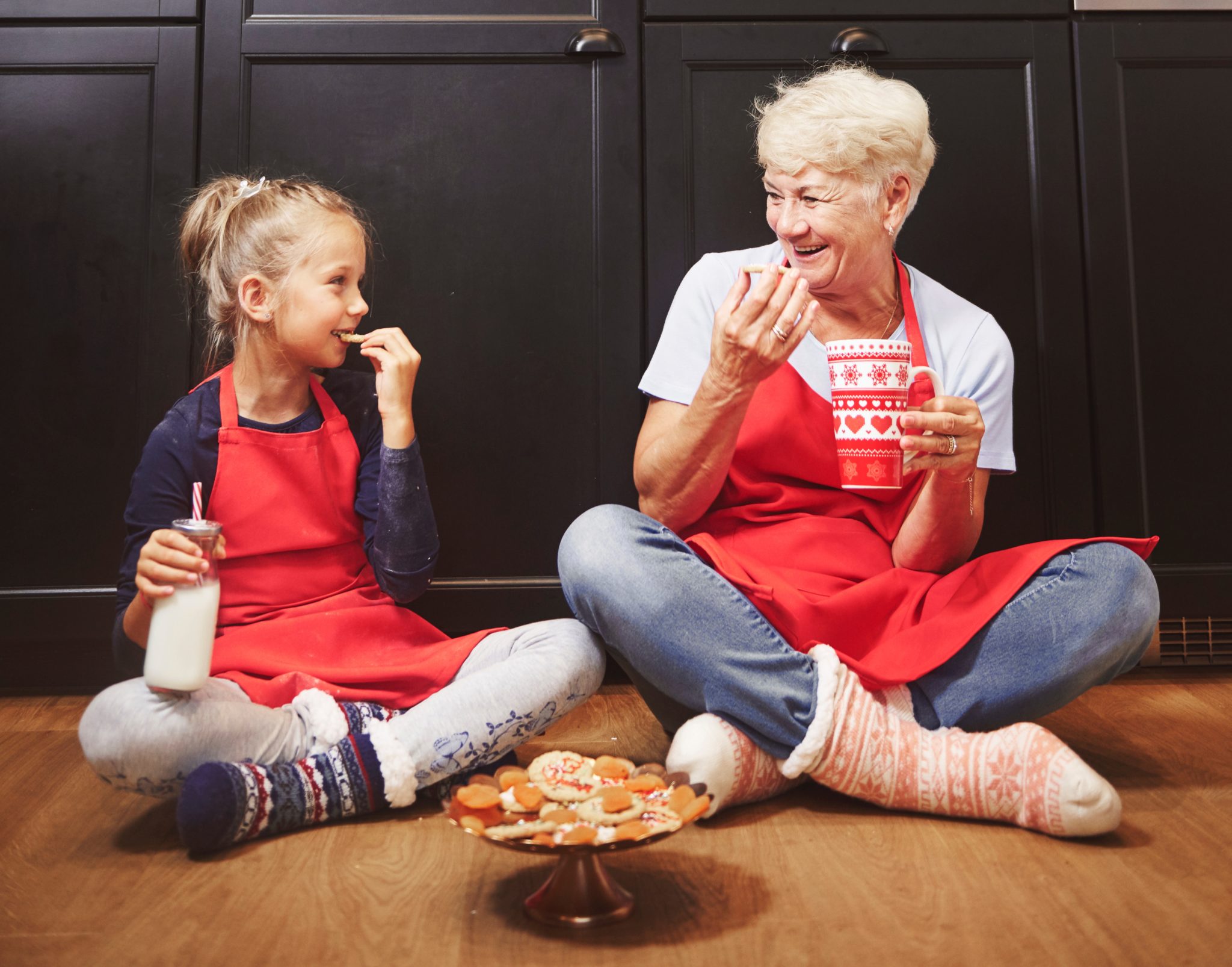 Girl and grandma eating Christmas cookies on the floor