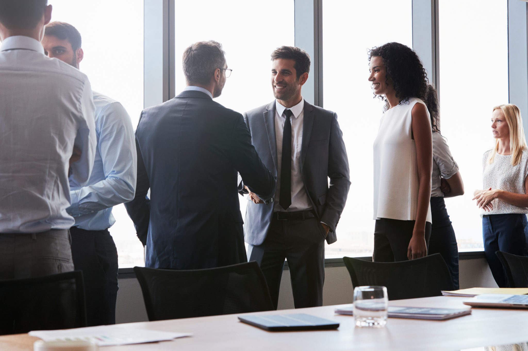 Businesspeople Shaking Hands Before Meeting In Boardroom
