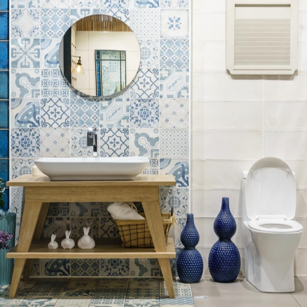 bathroom with toilet and wooden sink a round mirror and blue pattered wallpaper