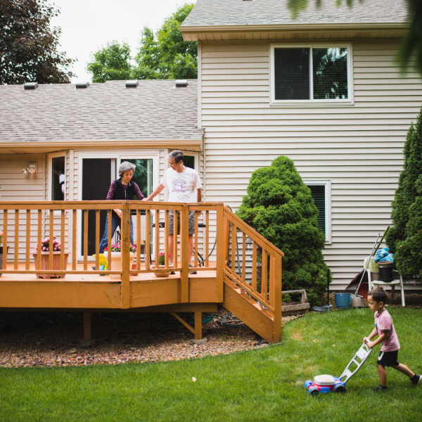 deck with people on it and a little girl playing in the yard