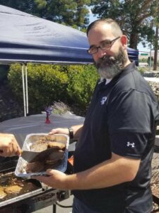 Branch Manager John loads burgers in a tray at Sierra's annual Mill Street BBQ