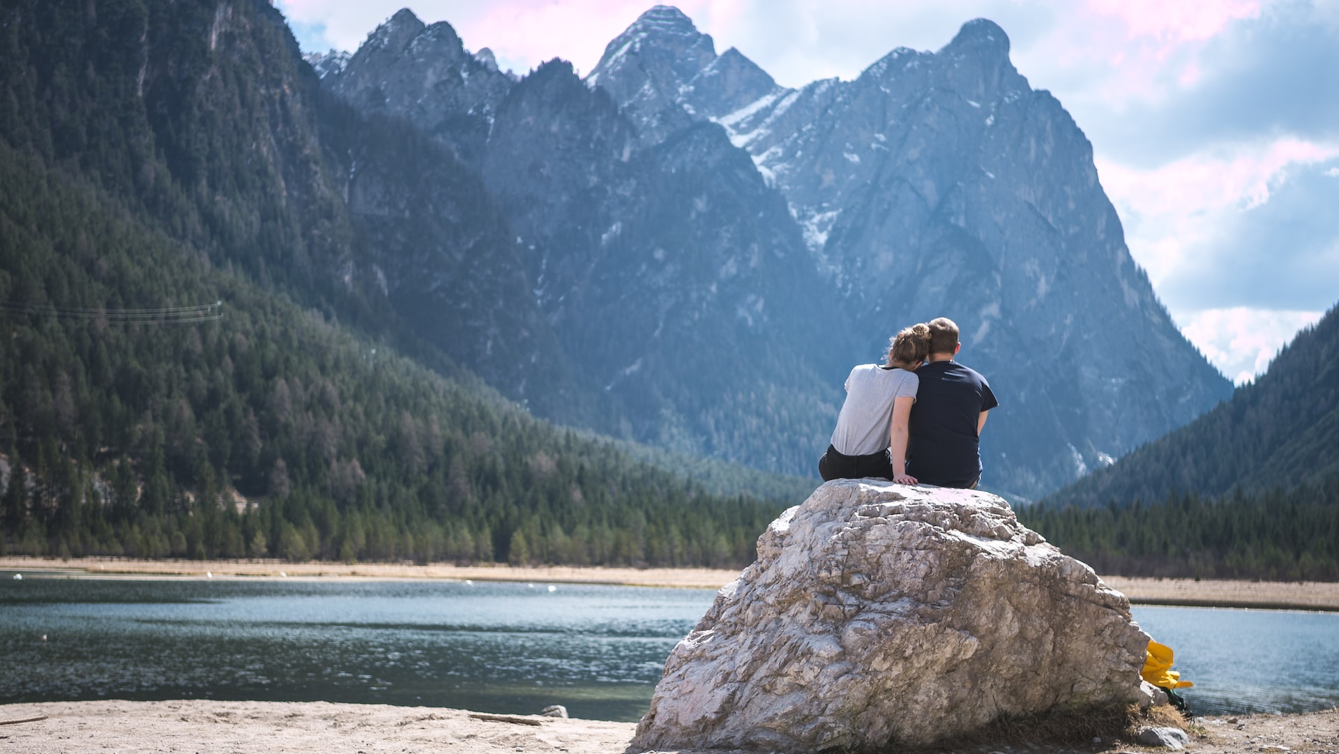 couple embraced on a rock in front of a lake