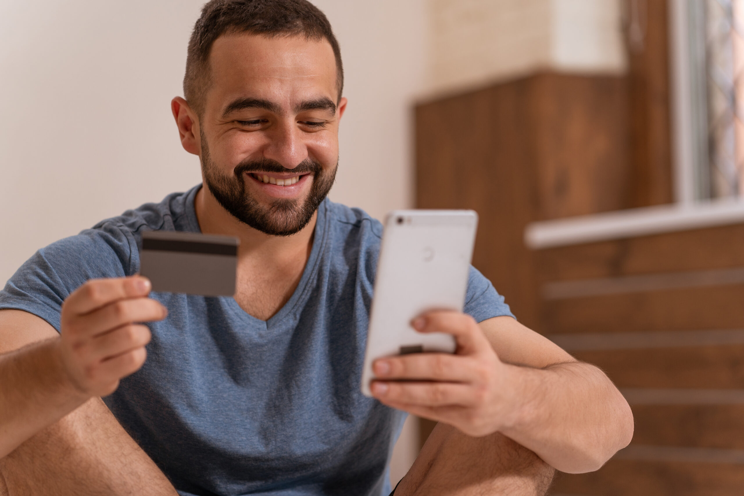 Man smiling looking at his phone and card